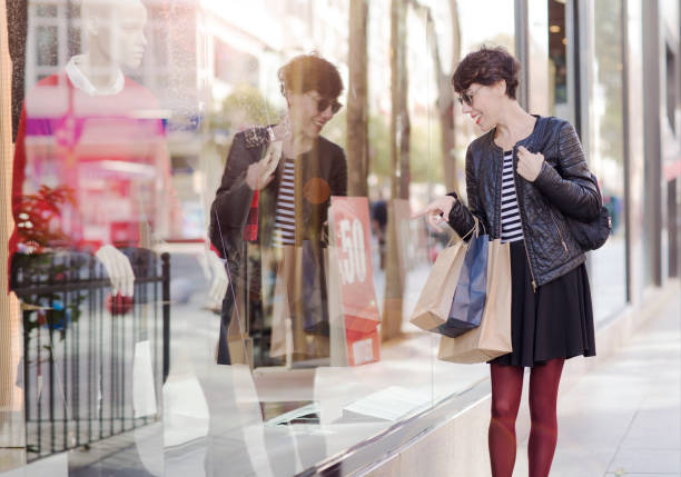 Woman looking at store window with her reflection on glass.