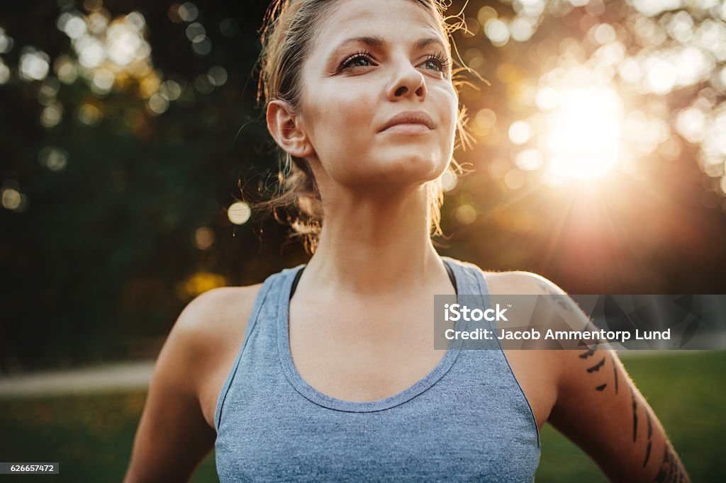 Confident fitness model in park Close up portrait of fit young woman in sportswear standing outdoors and looking away. Confident fitness model in park. Women Stock Photo