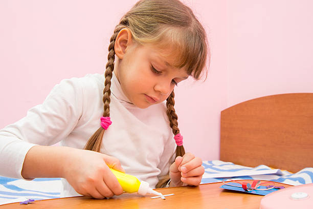 ragazza applicare la colla ai mestieri di carta colorata - family album foto e immagini stock