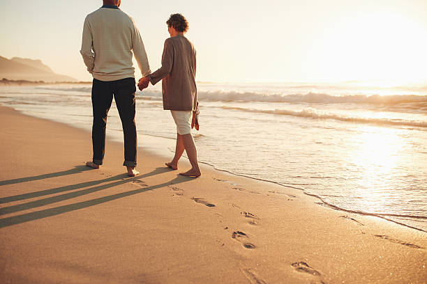 해안을 따라 걷는 시니어 커플 - men footprint beach sunset 뉴스 사진 이미지