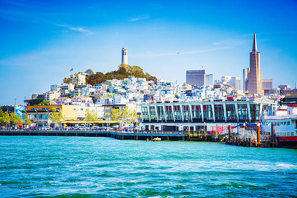 Downtown San Francisco view from Bay on sunny day with Coit tower, telepgraph hill and a pier.
