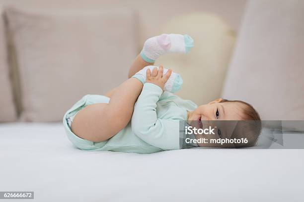 Playful Baby Lying Down In Bed Stock Photo - Download Image Now - 2-5 Months, Baby - Human Age, Diaper