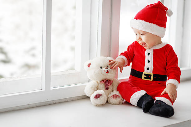 istock happy baby dressed as Santa Claus sitting on window 626670284