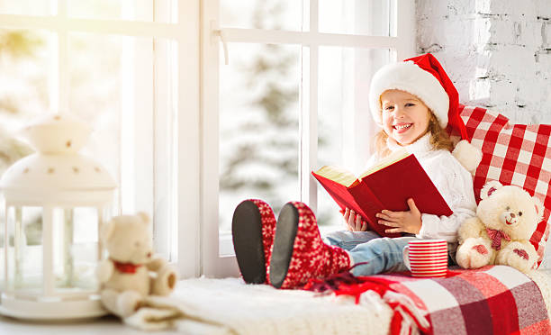 istock happy child reading a book while sitting at winter window 626670960