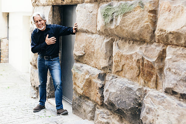 Senior walking through city, having heart attack