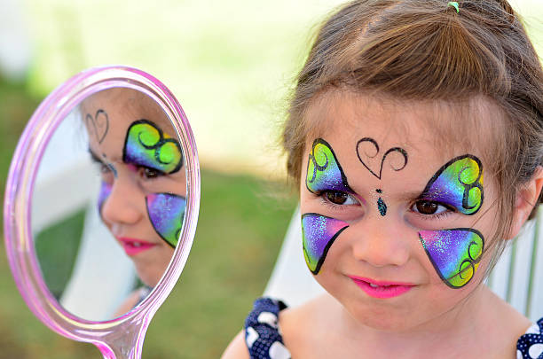 little girl getting with face  looks at the mirror. Focus on face.