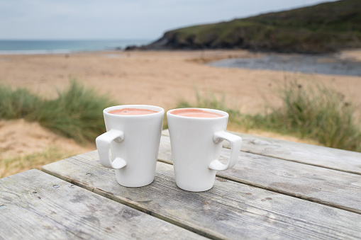 Hot chocolate drink on the beach at poldhu cove in winter, The Lizard Cornwall.