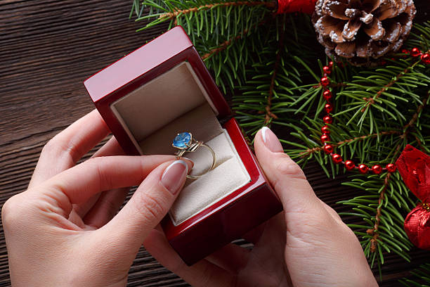 istock Engagement ring in female hands among Christmas decorations on wood 626681920
