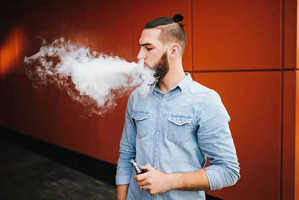 vaping. casual men with beard vaping an electronic cigarette. - one person looking at camera male posing imagens e fotografias de stock