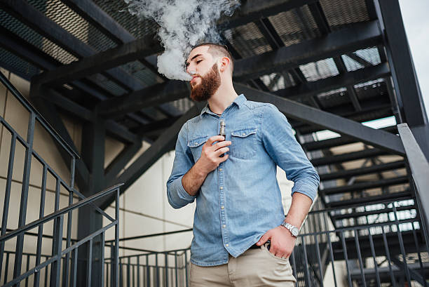 portrait of vaper vaping a vaporizer outdoors. safe smoking. - one person looking at camera male posing imagens e fotografias de stock