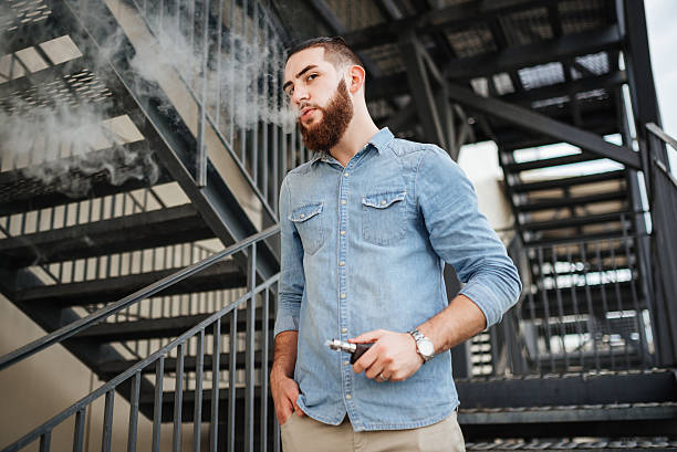 vaping. casual men with beard vaping an electronic cigarette. - one person looking at camera male posing imagens e fotografias de stock