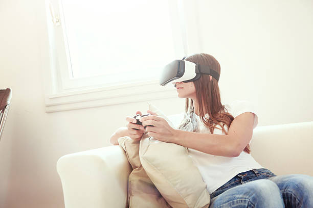 istock Young woman sitting on couch, using VR glasses 626685848