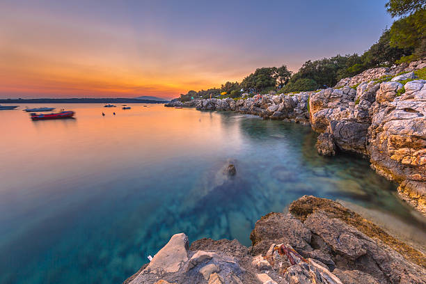 colorida puesta de sol sobre la costa rocosa de croacia - krk fotografías e imágenes de stock