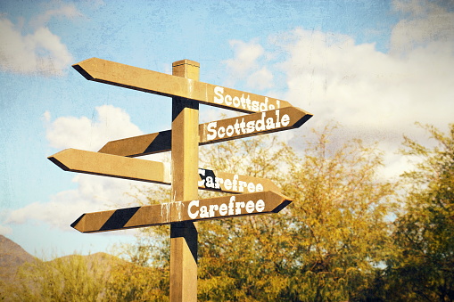 A directional sign in Cave Creek, Arizona points to Scottsdale and Carefree.  Image processed with vintage effects.