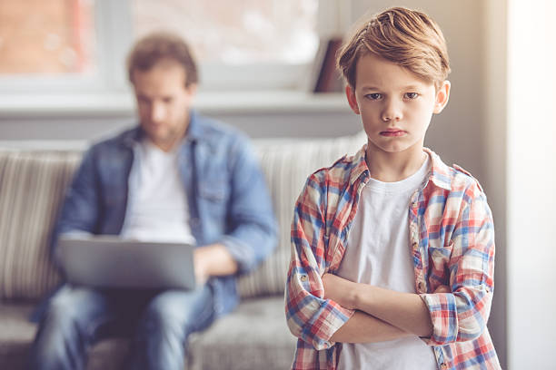 Father and son Sad little boy is looking at camera while his father is working in the background Rudeness stock pictures, royalty-free photos & images