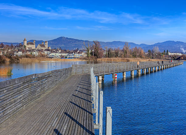 Rapperswil, Switzerland - 30 November, 2016: people on the wooden pedestrian bridge over Lake Zurich between the town of Rapperswil and the village of Hurden - the longest wooden bridge in Switzerland. 