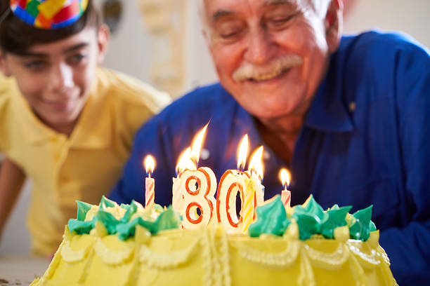 ケーキの誕生日パーティーでろうそくを吹く少年と先輩 - birthday family party cake ストックフォトと画像