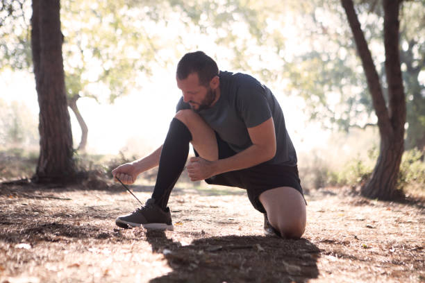istock Young man tying his shoelaces in park 626703308