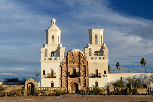 San Xavier Mission at sunrise, Tucson, Arizona, USA. San Xavier Mission is a Catholic mission founded in 1692. It is a national historic landmark located 9 miles south of downtown Tucson. The mission 's interior is filled with original statues and mural paintings of 18th century. It is a popular tourist destination.