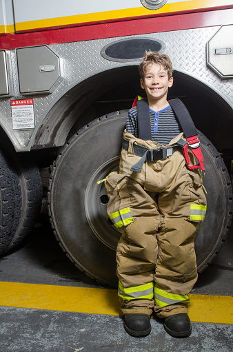 Niño con pantalones adultos de bombero real además de camión de bomberos photo