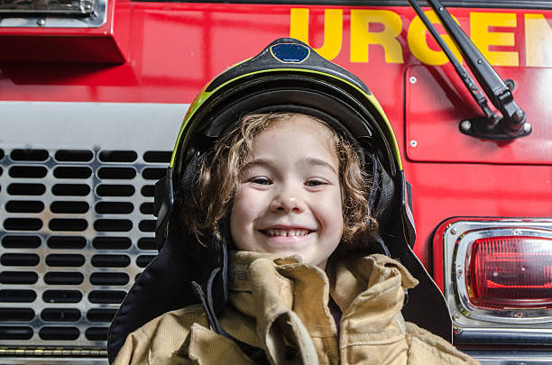 消防士のコートとヘルメットを身に着けている若い女の子 - fire retardant ストックフォトと画像