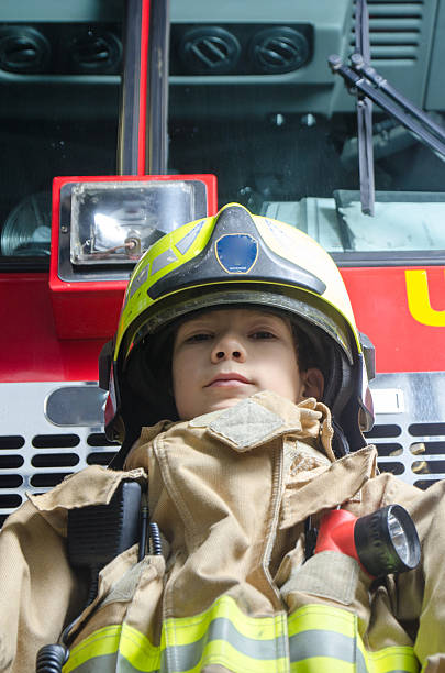 istock Young boy wearing fireman coat and helmet 626723862