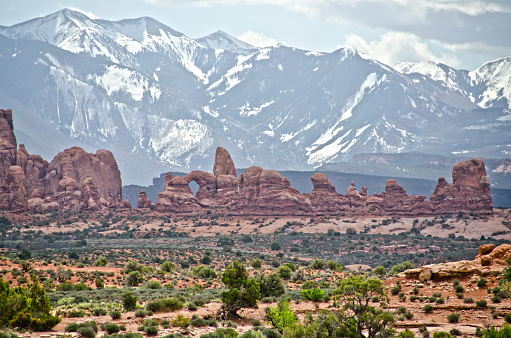 The Windows section of Arches National Park includes Turret Arch, seen in the left center portion of the image, with vast desert vegetation in the foreground and the snowy La Sal Mountains in the background.