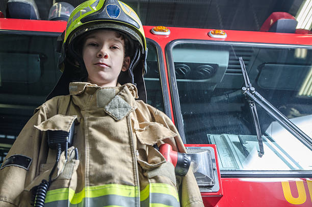 istock Young boy wearing fireman coat and helmet 626723916
