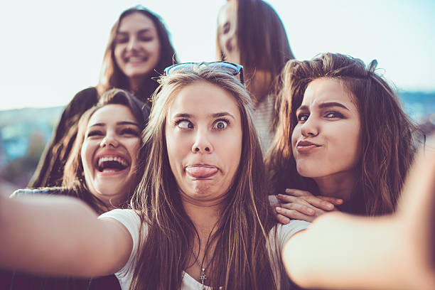 Group of Crazy Girls Taking Selfie and Making Faces Outdoors Group of teen friends how smiling, making faces and taking selfie with their mobile smartphone outdoor on the city street. teasing photos stock pictures, royalty-free photos & images