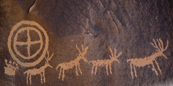 Newspaper Rock State Historic Monument, located in southeastern Utah close to the Needles District of Canyonlands National Park, has sandstone rock faces covered with petroglyphs drawn over 2,000 years ago by Anasazi, Pueblo and Archaic Native Americans.  The drawings consist of peoples, animals and symbols and were created in the desert varnish that builds up on the walls of the sandstone when iron and manganese from rainfall and bacteria are deposited.