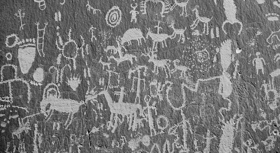 Newspaper Rock State Historic Monument, located in southeastern Utah close to the Needles District of Canyonlands National Park, has sandstone rock faces covered with petroglyphs drawn over 2,000 years ago by Anasazi, Pueblo and Archaic Native Americans.  The drawings consist of peoples, animals and symbols and were created in the desert varnish that builds up on the walls of the sandstone when iron and manganese from rainfall and bacteria are deposited.