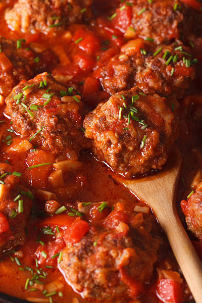 Mashed potatoes with meatballs in tomato sauce on white plate on wooden background