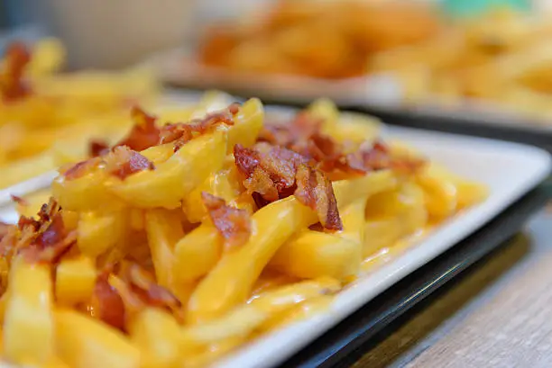 Photo of French fries and cheese with bacon on top