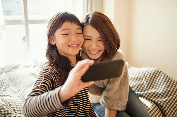 istock Mother and daughter taking a selfie in bed room 626771378