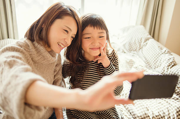 istock Mother and daughter taking a selfie in bed room 626771574