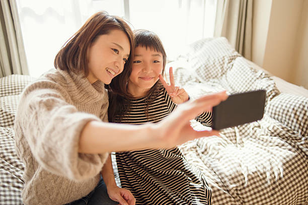 istock Mother and daughter taking a selfie in bed room 626771630