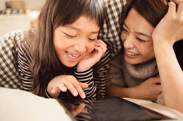 istock Mother and daughter playing with a digital tablet in bedroom 626774416
