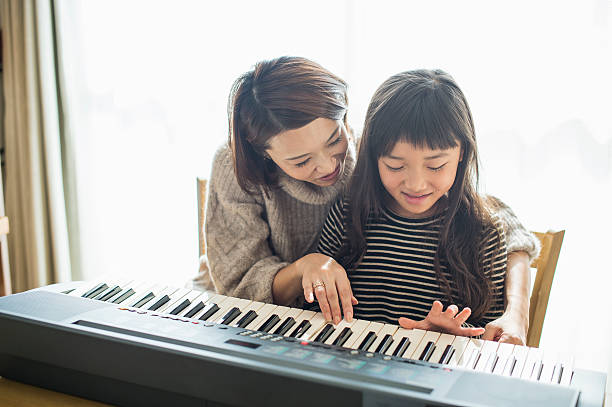 istock Mother and daughter playing  on electronic piano 626776346