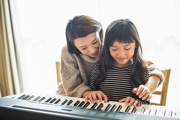 istock Mother and daughter playing  on electronic piano 626776430