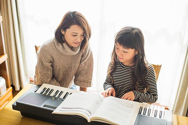 istock Mother and daughter playing  on electronic piano 626776524