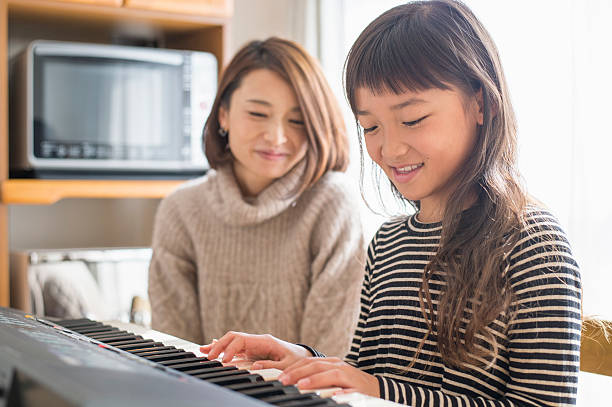 istock Mother and daughter playing  on electronic piano 626776576