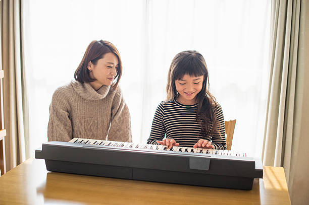 istock Mother and daughter playing  on electronic piano 626776654