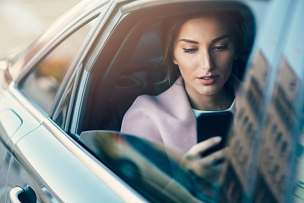 mujer usando un teléfono inteligente en un coche - on the phone women beautiful beauty fotografías e imágenes de stock