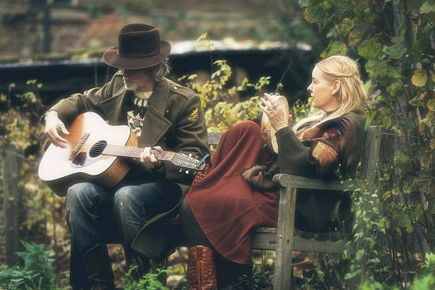 秋の庭のベンチで音楽を作る男女。 - 1970s style hippie couple retro revival ストックフォトと画像