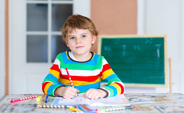 istock Happy school kid boy at home making homework 626783412