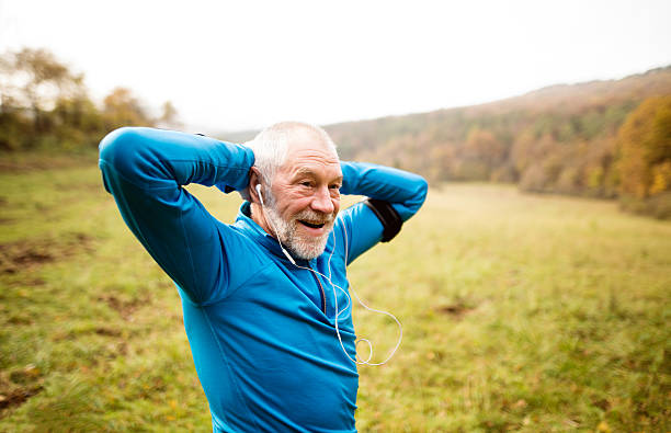 senior läufer mit armbinde beim dehnen. herbst natur. - adult jogging running motivation stock-fotos und bilder
