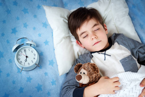 istock six years old child sleeping in bed with alarm clock 626786722