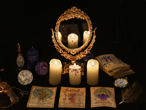 Fortune telling ritual with the Tarot cards, mirror, crystals and vintage objects. Halloween concept, black magic still life or witch spell with occult and esoteric symbols, divination rite