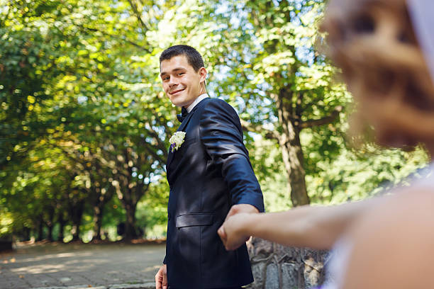 heureux couple dans un parc - wedding suit photos et images de collection