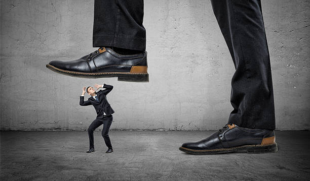 istock Tiny frightened businessman under feet of huge man 626799312